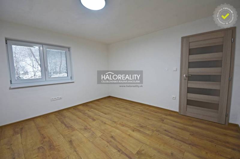 Prázdný pokoj v rodinném domě s podlahou s dřevěným dekorem a oknem.