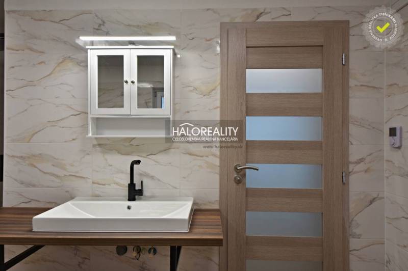 Koupelna s umyvadlem, černou vodovodní baterií a skříňkou v rodinném domě.