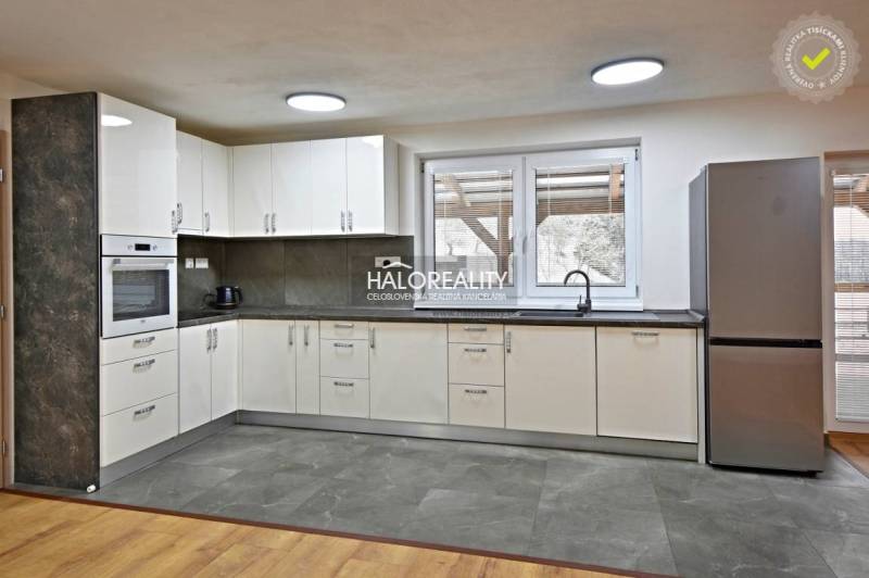 Kuchyně v rodinném domě s moderními spotřebiči a podlahou s dřevěným dekorem.