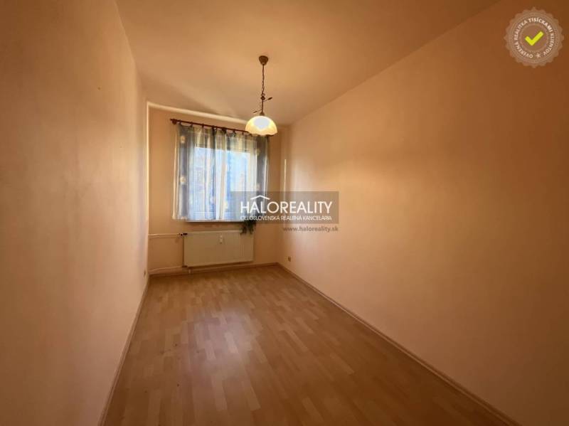 Úzký světlý prostor s oknem, závěsy a podlahou s dřevěným dekorem v 3-pokojovém bytě.