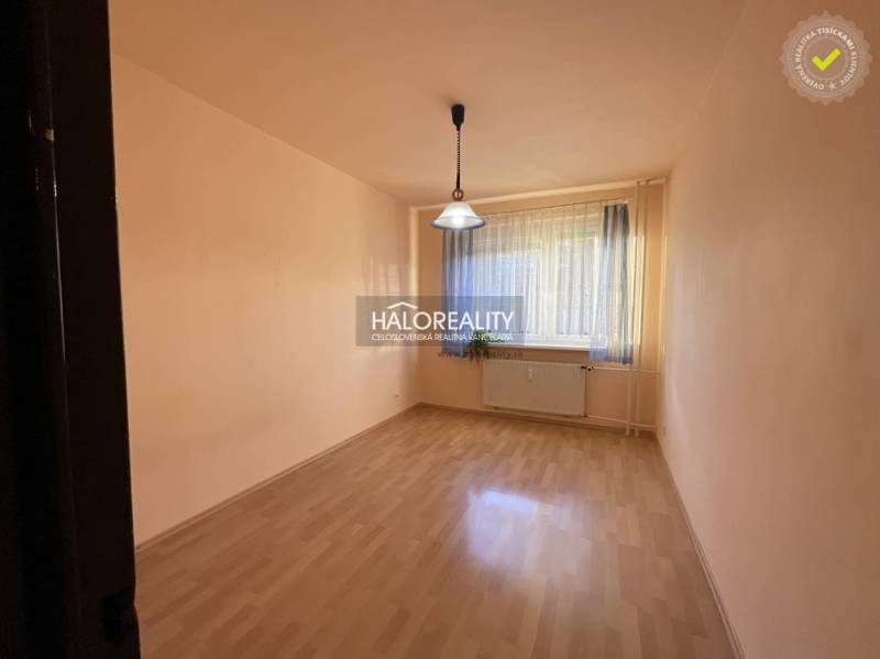 Prázdná místnost s oknem, závěsem, podlahou s dřevěným dekorem, světlem a radiátorem.