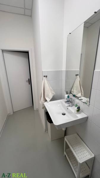 Koupelna v kancelářích s umyvadlem, ručníky a čisticími prostředky.