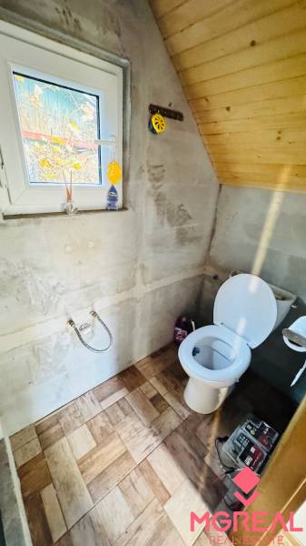 Toaleta v dřevěné chatě, s podlahou s dřevěným dekorem a oknem.