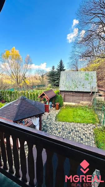 Zahrada u chaty v Partizánském s altánkem a stromy v pozadí.