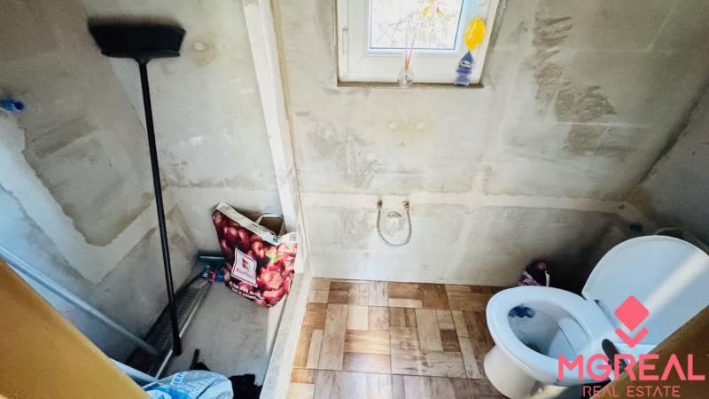 Koupelna v chatě s podlahou s dřevěným dekorem, WC a oknem.