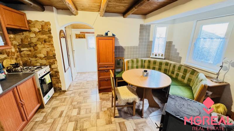 Rustikální kuchyně na chatě s plynovým sporákem a rohovou sedačkou.