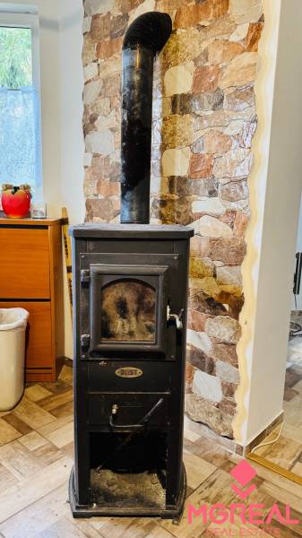 Krbová kamna s komínem, kamenná stěna, podlaha s dřevěným dekorem v chatě.