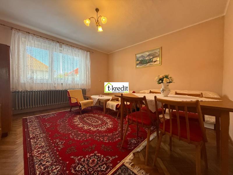 Obývací pokoj v rodinném domě s kobercem, dřevěným nábytkem a podlahou s dřevěným dekorem.