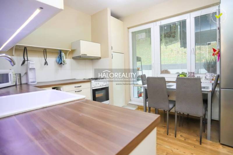 Kuchyně v 2-pokojovém bytě s podlahou s dřevěným dekorem, jídelním stolem a spotřebiči.