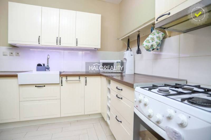 Kuchyně v 2-pokojovém bytě s rustikálními skříňkami a plynovým sporákem, světlý design.