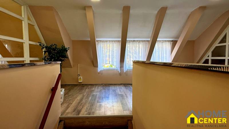 Interiér budovy s podlahou s dřevěným dekorem, velkým oknem a rostlinou.