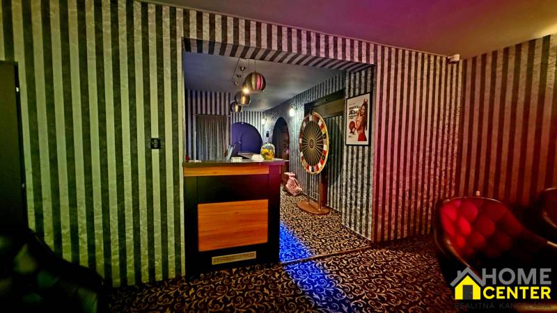 Interiér budovy s černobílými pruhovanými tapetami a vzorovaným kobercem.