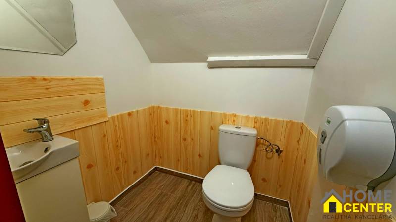 Koupelna s dřevěným obkladem, sanitou a podlahou s dřevěným dekorem, zrcadlo na stěně.