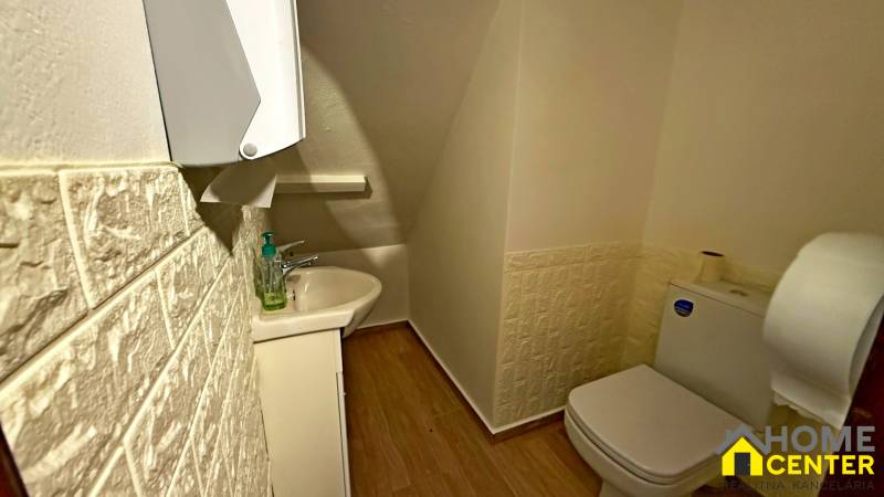 Koupelna s umyvadlem, toaletou, podlahou s dřevěným dekorem a texturovanými stěnami.