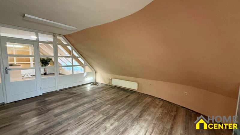 Interiér budovy s podlahou s dřevěným dekorem a šikmou světle hnědou stěnou.