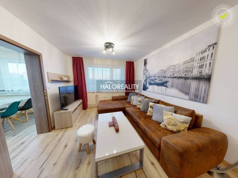 Obývací pokoj v 2-pokojovém bytě s hnědou sedačkou a podlahou s dřevěným dekorem.