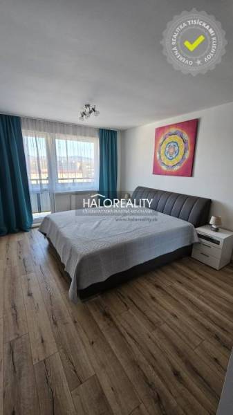 Ložnice v dvoupokojovém bytě s podlahou s dřevěným dekorem a uměním na stěně.