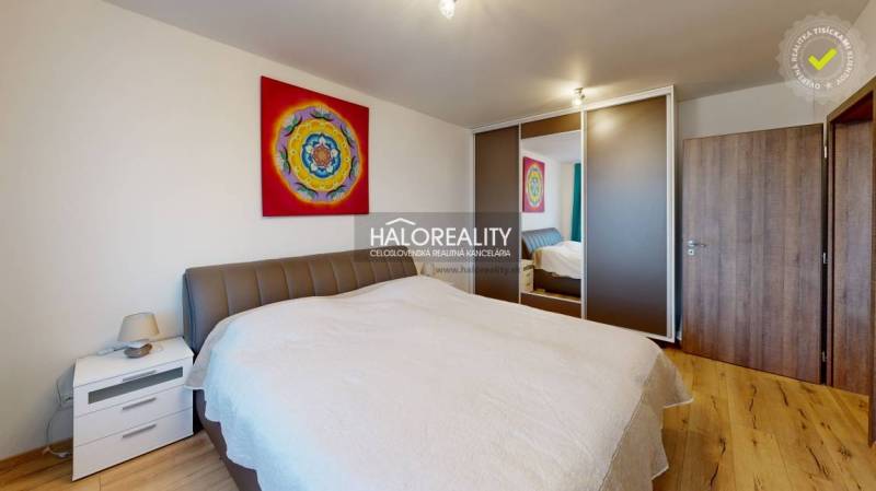 Ložnice v 2-pokojovém bytě s podlahou s dřevěným dekorem a barevným obrazem.