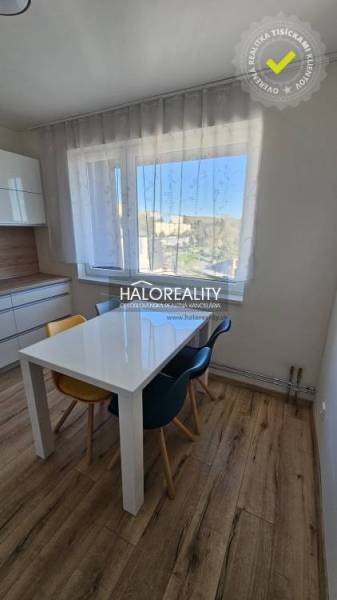Jídelní kout s oknem v 2-pokojovém bytě a podlahou s dřevěným dekorem.