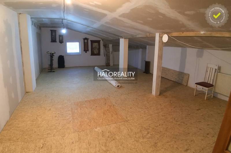 Podkrovní prostor s oknem v rodinném domě, podlaha s dřevěným dekorem, cvičební kolo.