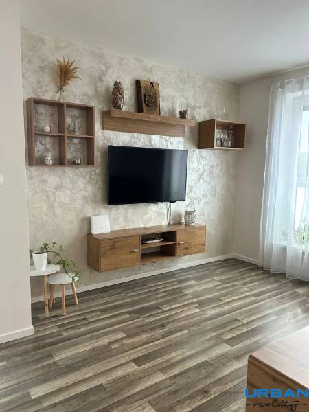 Obývací pokoj v 3-pokojovém bytě s podlahou s dřevěným dekorem, zavěšenou TV a dekoracemi.