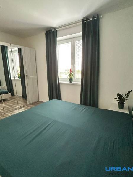 Ložnice v 3-pokojovém bytě se zrcadlovou skříní, závěsy a podlahou s dřevěným dekorem.