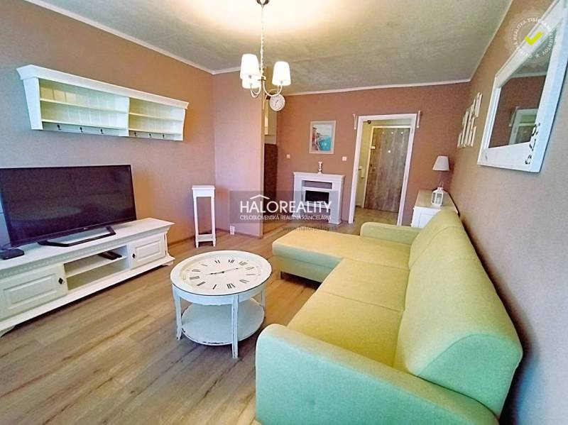 Obývací pokoj v 2-pokojovém bytě se světlou pohovkou a podlahou s dřevěným dekorem.