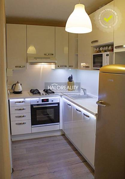 Kuchyně v 2-pokojovém bytě s bílými skříňkami a podlahou s dřevěným dekorem.