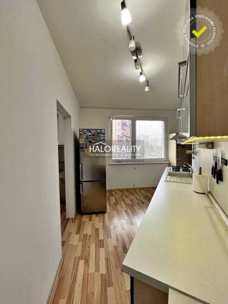 Kuchyně v 3-pokojovém bytě s podlahou s dřevěným dekorem a bílými stěnami.