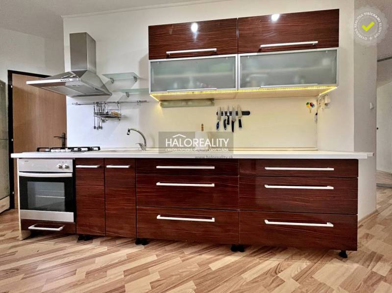 Kuchyně v 3-pokojovém bytě s kuchyňskou linkou a podlahou s dřevěným dekorem.