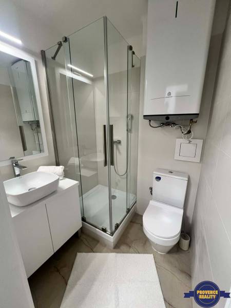Koupelna v 2-pokojovém bytě s moderním sprchovým koutem a umyvadlem.