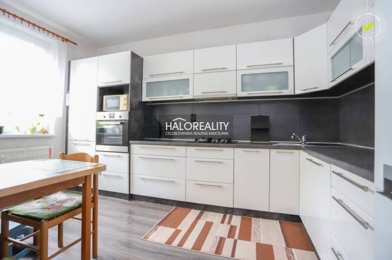 Kuchyně ve 3-pokojovém bytě s bílými skříňkami a podlahou s dřevěným dekorem.