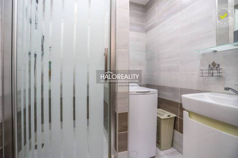 Koupelna s pračkou a sprchovým koutem v 3-pokojovém bytě, světlé obklady, čistý design.