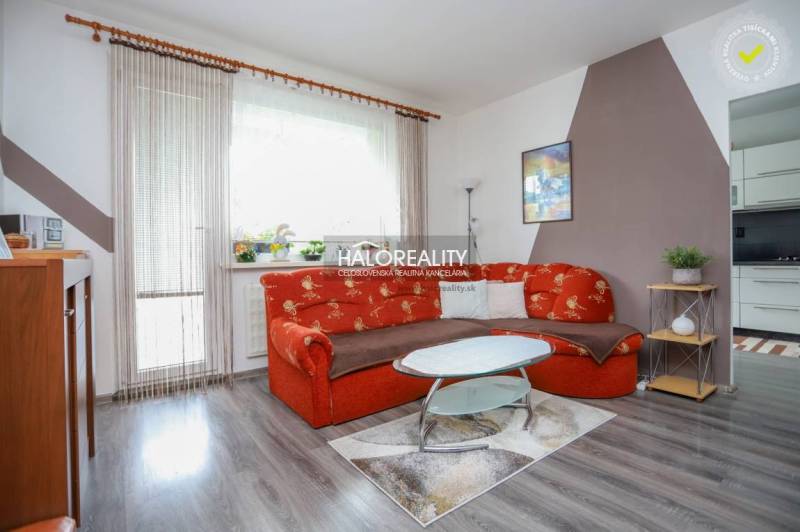 Obývací pokoj v 3-pokojovém bytě s oranžovou sedačkou a podlahou s dřevěným dekorem.