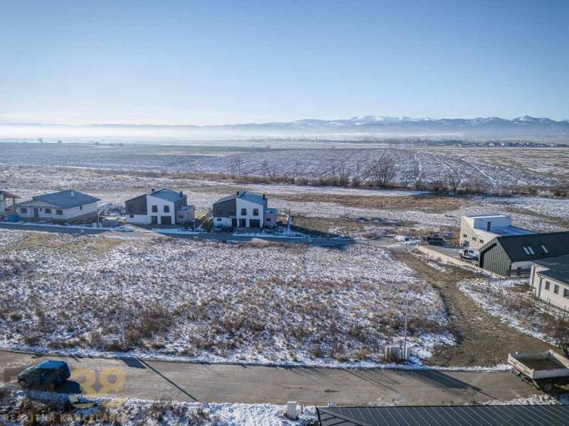 Mlynica: Pozemky - bydlení se zasněženými poli a domy, obklopené lesy a cestami.