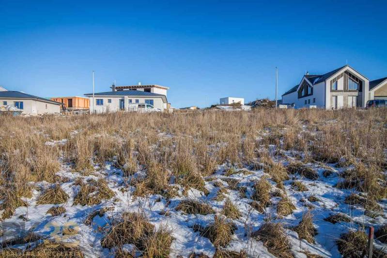 Pozemky - bydlení v Mlynici s výhledem na zasněžené hory a rodinné domy.
