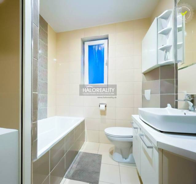 Koupelna s vanou a umyvadlem ve 2-pokojovém bytě, dominuje světlá dlažba.