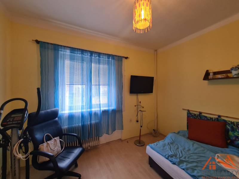 Pokoj v rodinném domě s cvičebním zařízením, křeslem a televizorem.