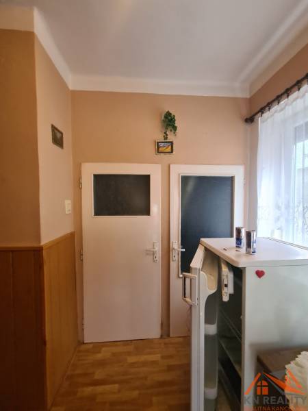 Interiér rodinného domu se dvěma dveřmi, lednicí a podlahou s dřevěným dekorem.