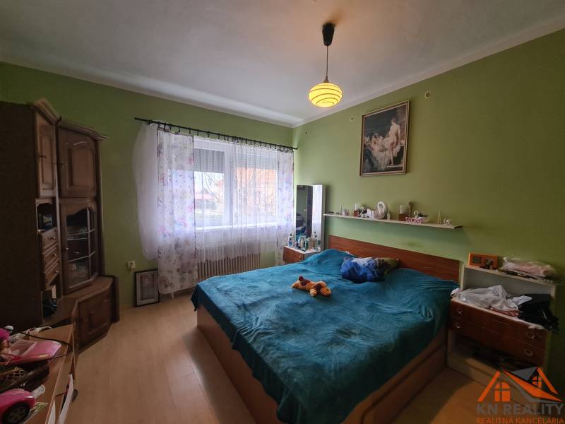 Ložnice v rodinném domě s podlahou s dřevěným dekorem a postelí.