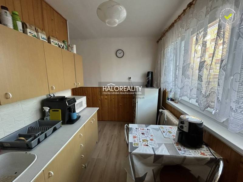 Kuchyně v 2-pokojovém bytě se spotřebiči a dlouhými záclonami přes okno.