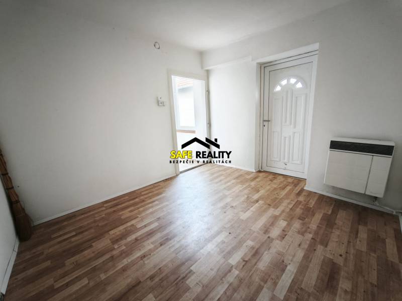 Interiér rodinného domu s podlahou s dřevěným dekorem a bílými stěnami.