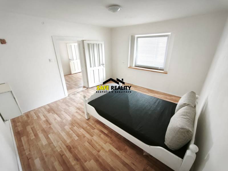 Světlý pokoj s postelí, podlaha s dřevěným dekorem, v rodinném domě.