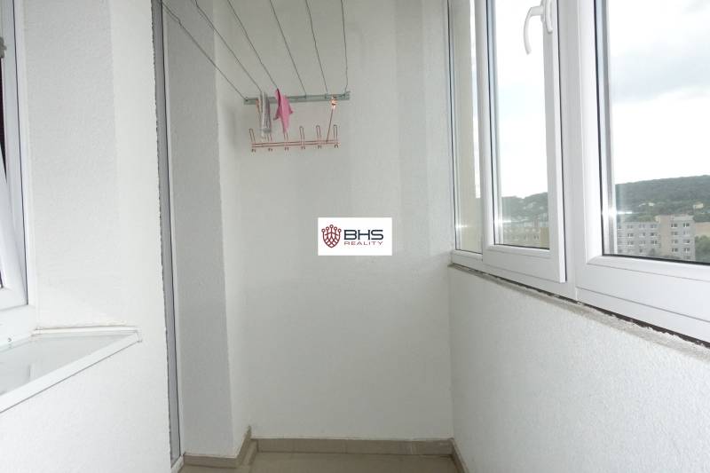 Zasklený balkon ve 3-pokojovém bytě s výhledem na městskou část.