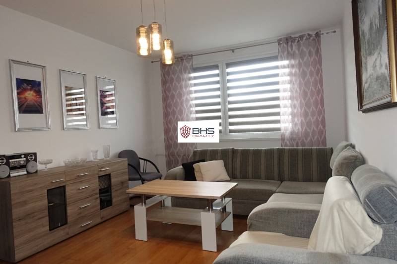 Světlý obývací pokoj s rohovou sedačkou, stolkem a komodou ve 3pokojovém bytě.