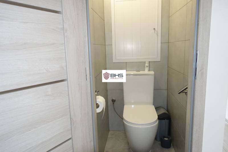 Koupelna v 3-pokojovém bytě s dlažbou a šedými stěnami.