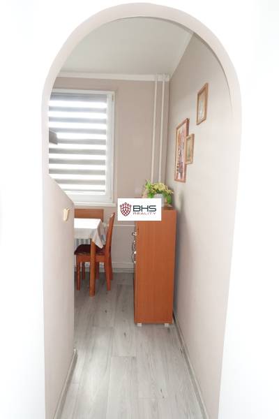 Chodba s obloukovým vstupem, podlaha s dřevěným dekorem, vede k jídelně v 3-pokojovém bytě.