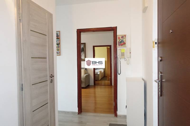 Chodba v 3-pokojovém bytě s podlahou s dřevěným dekorem a interkomem.