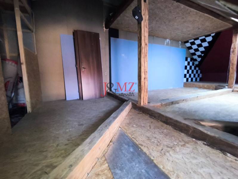 Podkrovní prostor v rodinném domě s dřevěnými prvky, šachovnicová stěna.