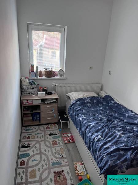 Dětský pokoj s postelí, oknem a koberečkem ve 4-pokojovém bytě.